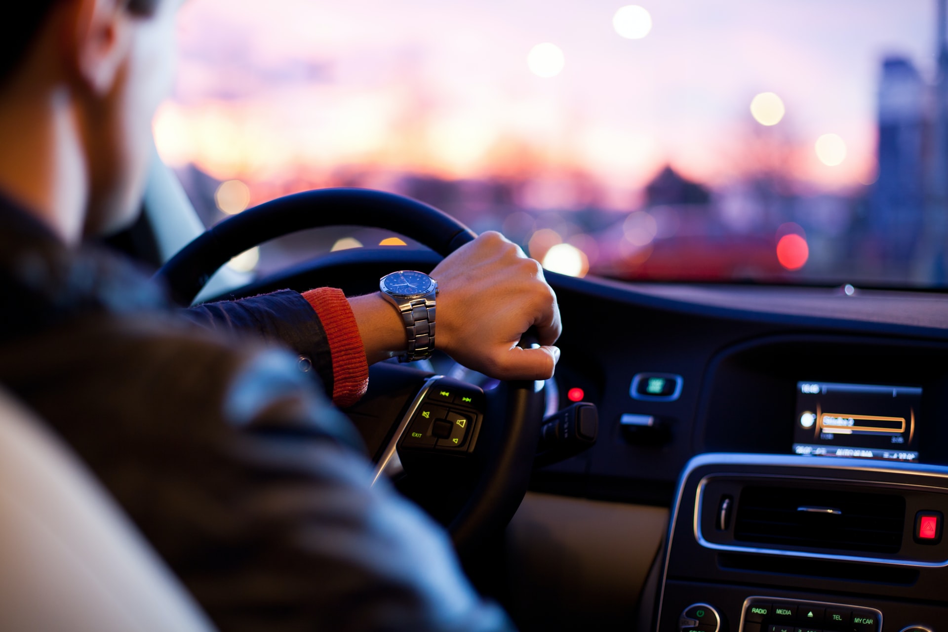 Mann mit einer Hand am Steuerrad in Auto