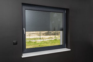 Ein großes Fenster in einem Raum mit schwarzen Wänden, mit halb heruntergelassenen Außenrollläden