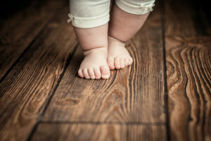 Babyfüße machen die ersten Schritte auf Holzfußboden