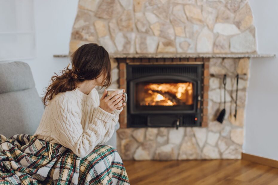 Frau mit Tasse vor Kamin im Wohnzimmer